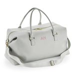 Load image into Gallery viewer, A gray leather duffel bag with a gold zipper and handles, featuring a personalized monogram on the front.