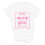Load image into Gallery viewer, A white short-sleeve crewneck t-shirt with a pink graphic print on the front. The graphic features a wavy border, a bow illustration, and the text 'GOING TO THE Chapel GONNA GET Married' in pink lettering.