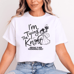 Load image into Gallery viewer, A woman wearing a white graphic t-shirt with a black hand-drawn style design that reads 'I'm Tying The Knot' and 'ABIGAIL'S HEN FUENGIROLA 2027', paired with light-wash blue jeans against a plain white background.
