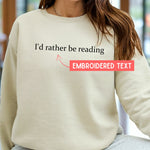 Load image into Gallery viewer, Beige sweatshirt with 'I'd rather be reading' text and an arrow pointing to it, with a blurred background.