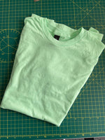 Load image into Gallery viewer, a green t - shirt sitting on top of a cutting board