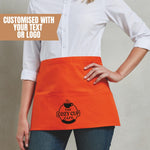 Load image into Gallery viewer, Woman wearing an orange personalised waist apron with an example café logo printed on the centre pocket