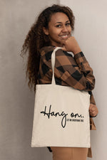 Load image into Gallery viewer, Woman carrying a natural Hang On Let Me Overthink This cotton tote bag over her shoulder