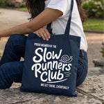 Load image into Gallery viewer, Woman sitting with a navy Slow Runners Club cotton tote bag