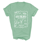 Load image into Gallery viewer, A mint green short-sleeve t-shirt with a white graphic print on the front. The graphic features various party-themed illustrations like a champagne bottle, cocktail glass, and lips, with the text 'KISS THE MISS goodbye', 'REBECCA'S HEN', and 'LEEDS 2027'.
