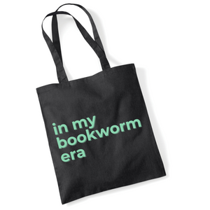 Black tote bag with 'in my bookworm era' text in green on a white background