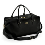 Load image into Gallery viewer, A black leather duffel bag with gold accents, featuring two handles and a zipper closure.
