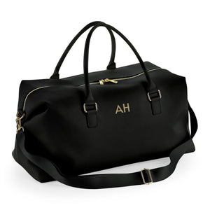 A black leather duffel bag with gold accents, featuring two handles and a zipper closure.