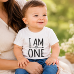 Load image into Gallery viewer, Child wearing a 'I AM ONE' shirt sitting on a woman's lap outdoors.
