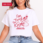Load image into Gallery viewer, A woman wearing a white graphic T-shirt with red text reading 'I'm Tying The Knot' and 'ABIGAIL'S HEN FUENGIROLA 2027', paired with light blue jeans. A red label in the top left says 'RED TEXT'.
