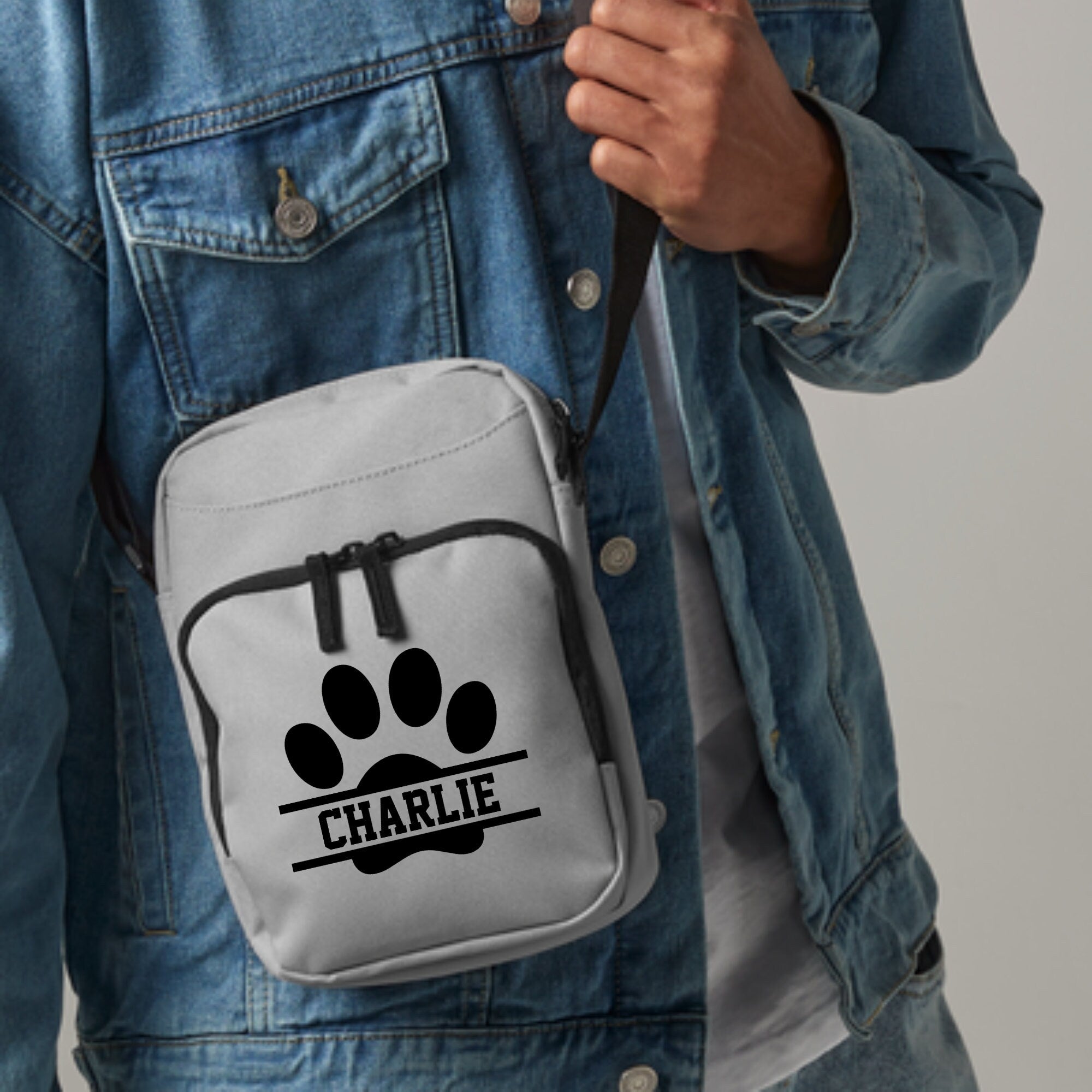 a person wearing a jean jacket holding a white bag with a dog paw on it