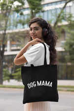 Load image into Gallery viewer, Woman carrying a black Dog Mama cotton tote bag over her shoulder
