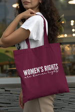 Load image into Gallery viewer, Woman carrying a burgundy Women's Rights Are Human Rights cotton tote bag over her shoulder
