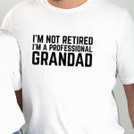 Load image into Gallery viewer, I'm Not Retired I'm A Professional Grandad men's t-shirt in white, close-up of the slogan worn by a model
